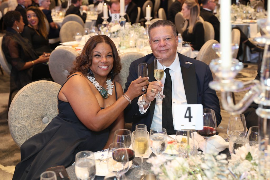 A couple at a table toasts with champagne glasses during the gala dinner.